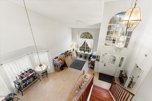 foyer entrance featuring tile patterned floors, an inviting chandelier, and a high ceiling