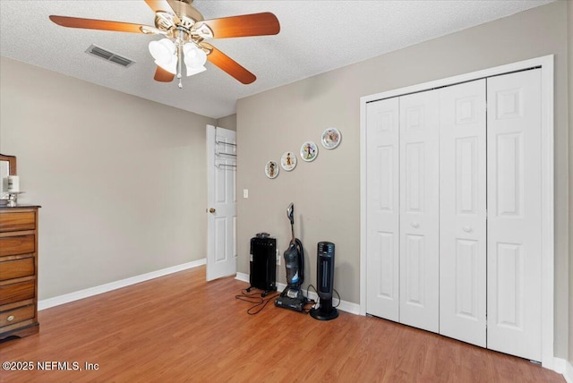 unfurnished bedroom with ceiling fan, a closet, hardwood / wood-style floors, and a textured ceiling