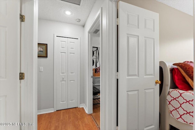 hall featuring a textured ceiling and light hardwood / wood-style floors