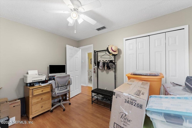 office space featuring ceiling fan, light hardwood / wood-style floors, and a textured ceiling