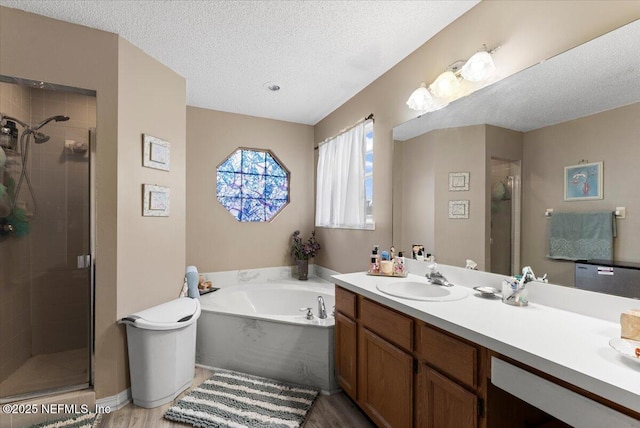 bathroom with vanity, hardwood / wood-style floors, a textured ceiling, and plus walk in shower