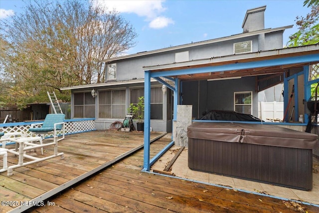 wooden deck with a sunroom and a hot tub