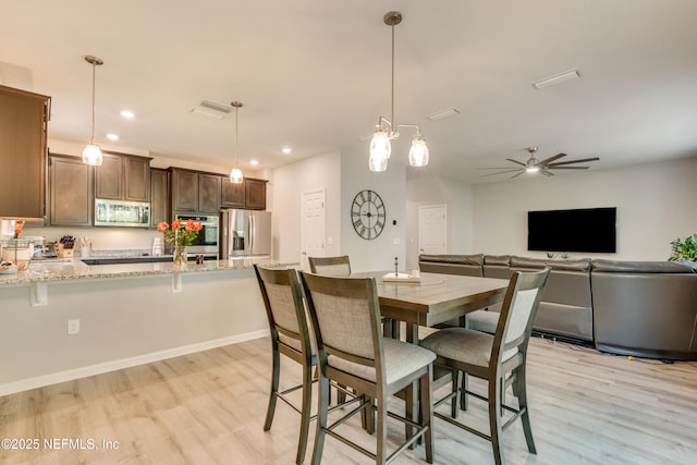 dining space with ceiling fan and light wood-type flooring