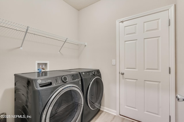 clothes washing area featuring washer and dryer and light hardwood / wood-style floors