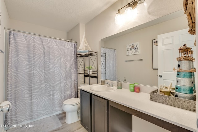 bathroom with hardwood / wood-style flooring, vanity, toilet, and a textured ceiling