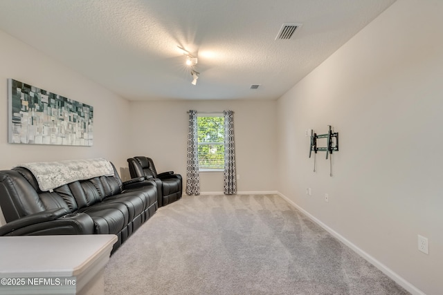 carpeted living room with a textured ceiling and rail lighting