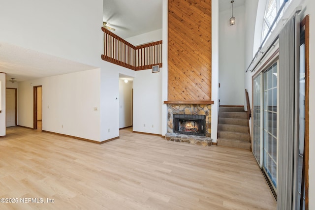 unfurnished living room featuring a high ceiling, light hardwood / wood-style floors, and a stone fireplace