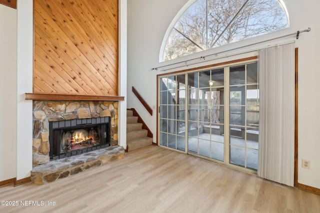 unfurnished living room with a fireplace, a high ceiling, and hardwood / wood-style flooring