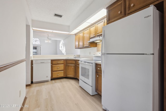 kitchen featuring sink, a chandelier, a textured ceiling, white appliances, and light wood-type flooring