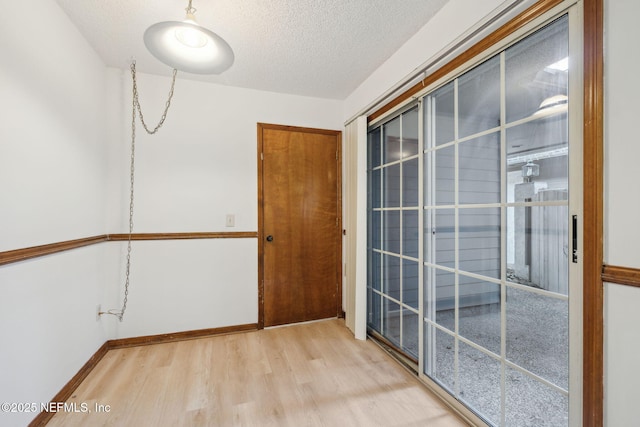 empty room with a textured ceiling and light hardwood / wood-style floors