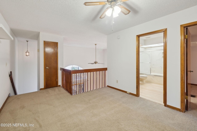 spare room featuring a textured ceiling, ceiling fan, and light carpet