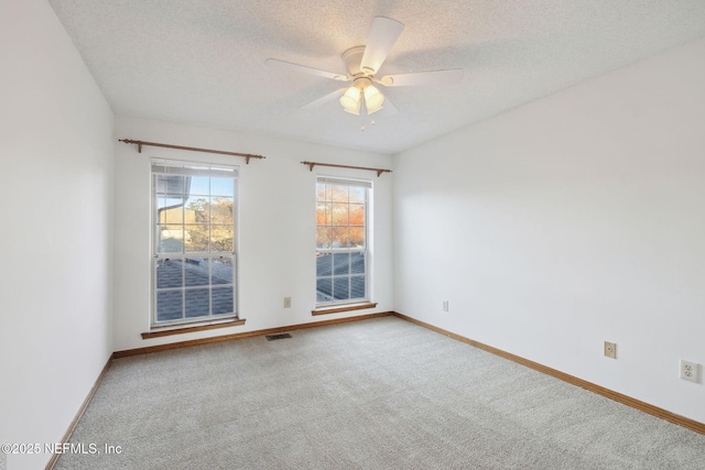 carpeted spare room featuring a textured ceiling and ceiling fan