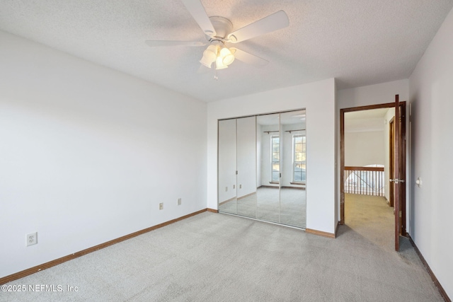 unfurnished bedroom with ceiling fan, a closet, light carpet, and a textured ceiling