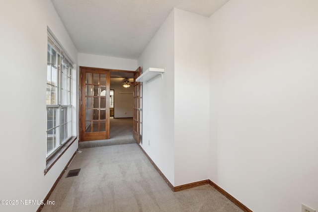 hallway featuring light carpet and french doors