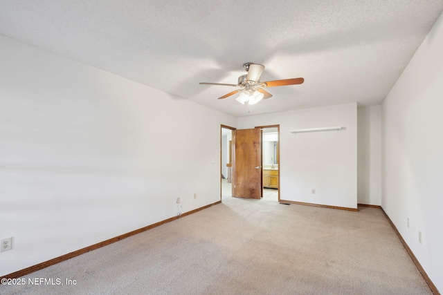 unfurnished bedroom with a textured ceiling, light colored carpet, ensuite bath, and ceiling fan