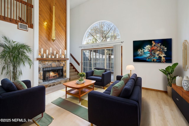 living room with a fireplace, a towering ceiling, and light hardwood / wood-style floors