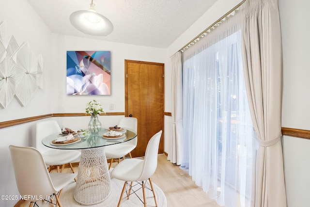 dining room with light wood-type flooring and a textured ceiling