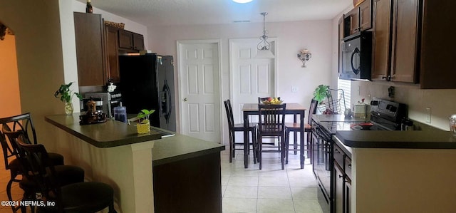 kitchen with kitchen peninsula, dark brown cabinetry, black appliances, light tile patterned floors, and hanging light fixtures