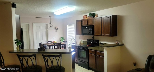 kitchen with black appliances, dark brown cabinets, kitchen peninsula, and a breakfast bar area