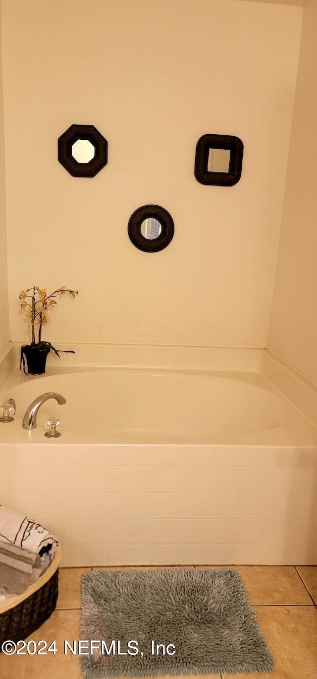 bathroom with tile patterned floors and tiled bath