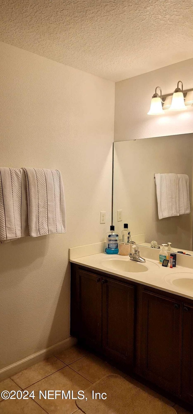 bathroom with tile patterned flooring, vanity, and a textured ceiling