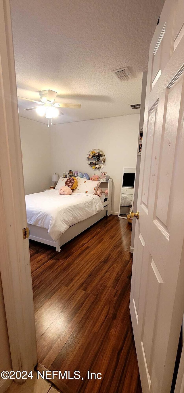 bedroom featuring a textured ceiling, ceiling fan, and dark wood-type flooring