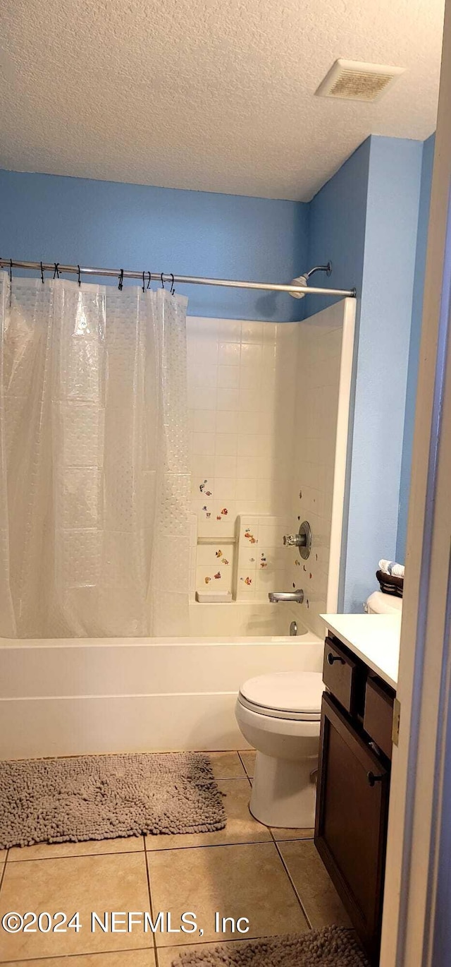 full bathroom with tile patterned floors, a textured ceiling, toilet, vanity, and shower / tub combo