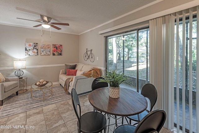 dining space with a textured ceiling, ceiling fan, and ornamental molding