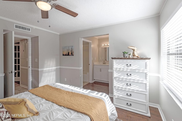 bedroom with ceiling fan, sink, dark hardwood / wood-style flooring, ensuite bathroom, and a textured ceiling