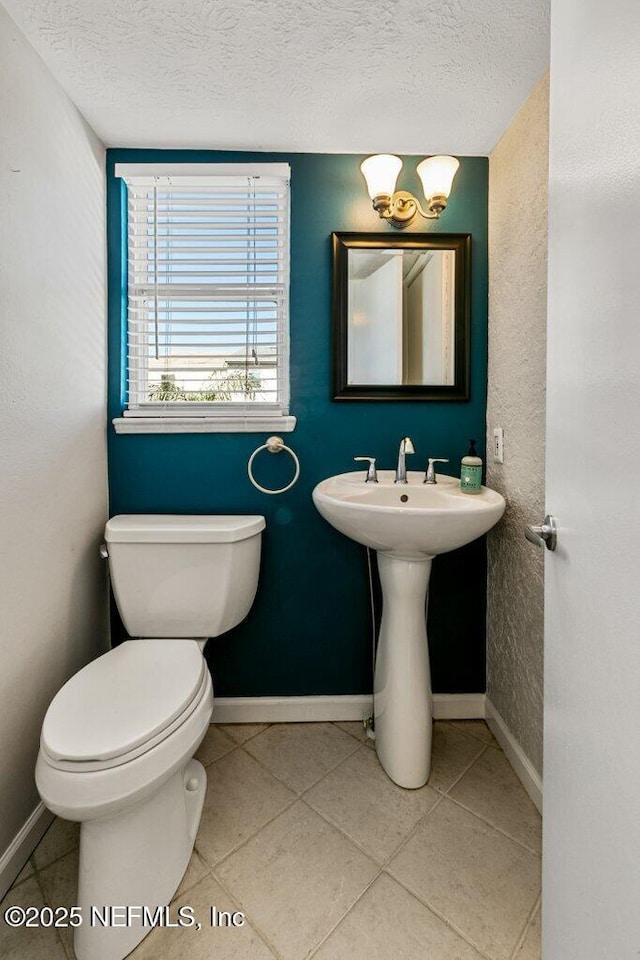 bathroom with tile patterned flooring, a textured ceiling, and toilet