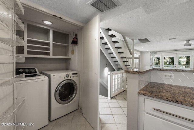 laundry area featuring washing machine and dryer, light tile patterned floors, and a textured ceiling