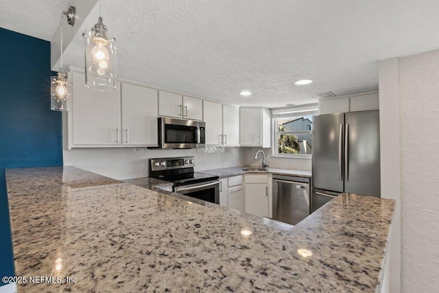 kitchen with stainless steel appliances, white cabinetry, light stone countertops, and sink