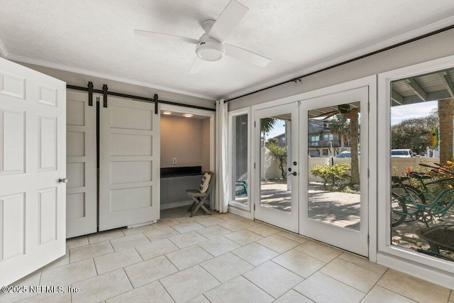 interior space with light tile patterned floors, crown molding, ceiling fan, a textured ceiling, and a barn door