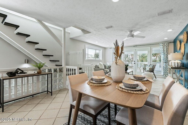 tiled dining area with a textured ceiling, french doors, and ceiling fan