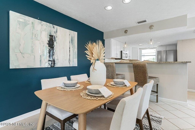 dining area with light tile patterned flooring and a textured ceiling