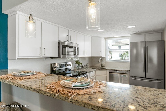 kitchen featuring sink, white cabinetry, hanging light fixtures, appliances with stainless steel finishes, and kitchen peninsula