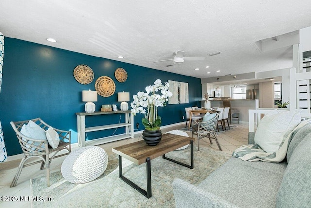 living room with light tile patterned flooring, ceiling fan, and a textured ceiling