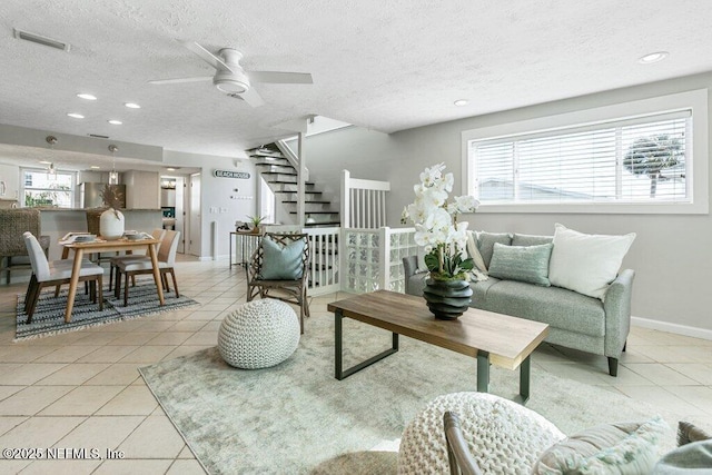 living room with ceiling fan, a textured ceiling, and light tile patterned floors