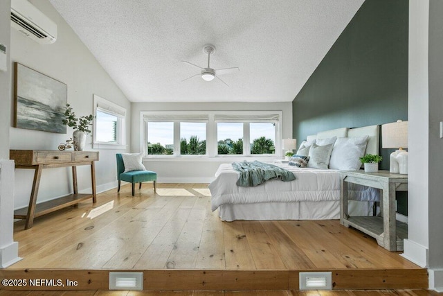 bedroom featuring lofted ceiling, hardwood / wood-style floors, a textured ceiling, and a wall mounted AC