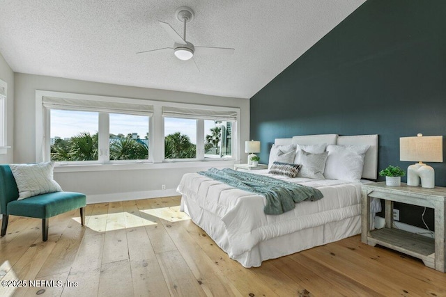 bedroom with multiple windows, wood-type flooring, a textured ceiling, and vaulted ceiling