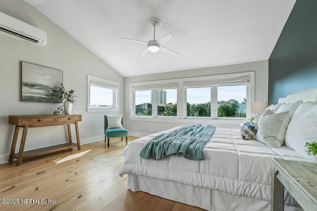 bedroom featuring lofted ceiling, wood-type flooring, a wall mounted AC, a textured ceiling, and ceiling fan