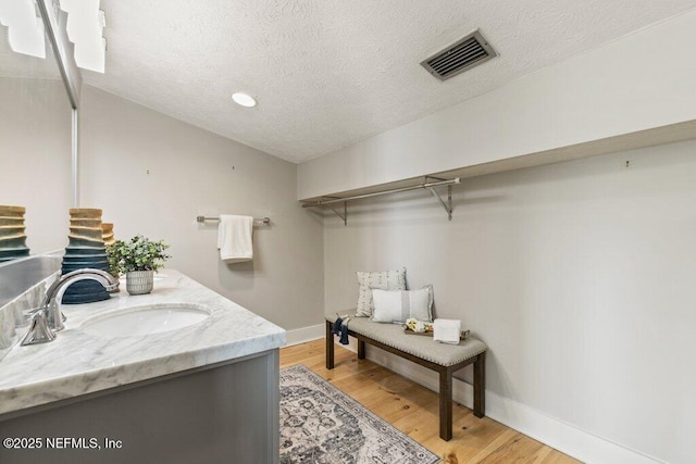 bathroom with hardwood / wood-style flooring, vanity, and a textured ceiling