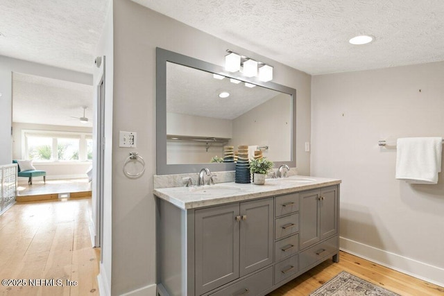 bathroom featuring vanity, hardwood / wood-style floors, ceiling fan, and a textured ceiling