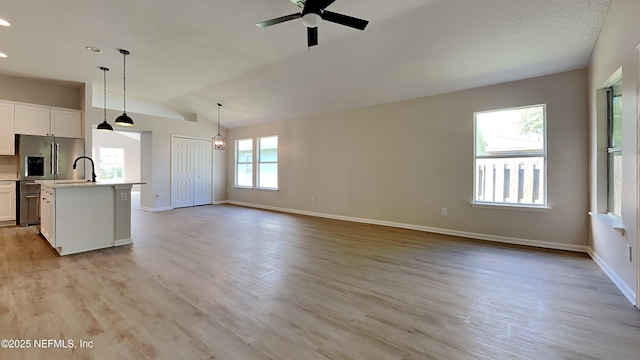 kitchen featuring a center island with sink, decorative light fixtures, light hardwood / wood-style floors, and white cabinetry