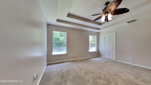 carpeted empty room featuring a tray ceiling, ceiling fan, and a textured ceiling