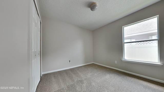 carpeted spare room with a textured ceiling and plenty of natural light