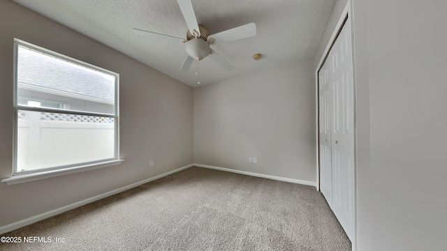 unfurnished bedroom featuring ceiling fan, a closet, light colored carpet, and a textured ceiling