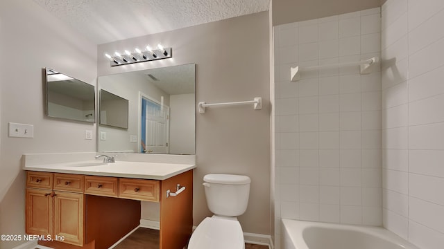 full bathroom featuring a textured ceiling, vanity, toilet, and tiled shower / bath combo