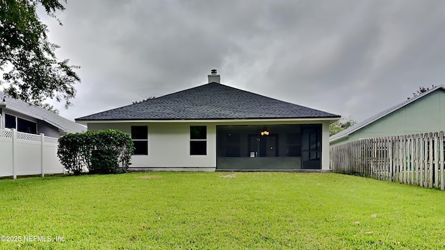 rear view of house with a lawn and a sunroom