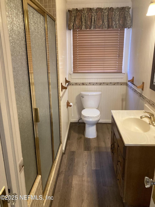 bathroom featuring a shower with door, vanity, wood-type flooring, and toilet